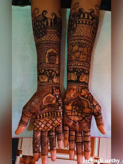 This bridal mehendi is filled with auspicious symbols for the wedding day. It includes a 'kalash' (ceremonial pot), 'Shubh Labh' (a blessing for prosperity), and bride and groom figures.