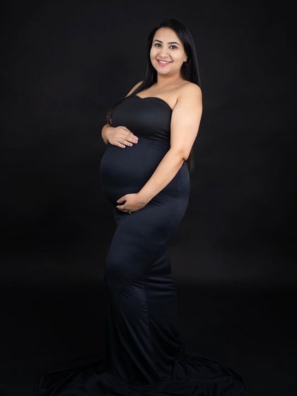 A simple and classic solo portrait against a black background. The focus is entirely on the mom-to-be and her beautiful baby bump.