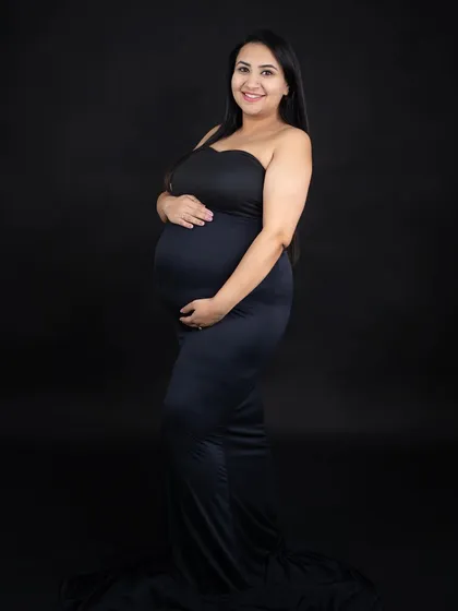A simple and classic solo portrait against a black background. The focus is entirely on the mom-to-be and her beautiful baby bump.