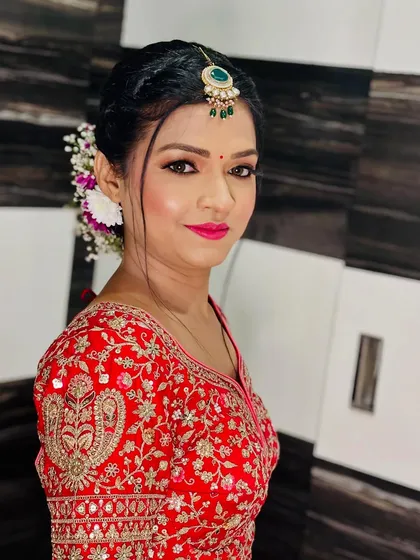 A close-up of the bride's makeup for her pheras. The look features a pop of pink on the lips and beautifully defined eyes, complementing her red lehenga.