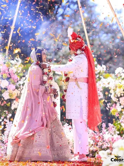 The Varmala ceremony, with the groom placing the garland on his bride amidst a shower of petals. A classic and beautiful wedding moment.
