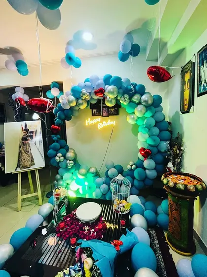 A surprise birthday decoration I did in someone's home. The blue and silver balloon ring, neon sign, and scattered rose petals on the table create a very special and intimate celebration.