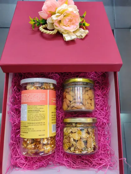 Another view of the red gift box, showing the neatly arranged jars of healthy and gourmet snacks.