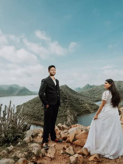 A powerful wide shot of the couple standing on a hilltop overlooking the winding lakes of Udaipur. This showcases the grand scale and epic beauty of our destination photoshoots.