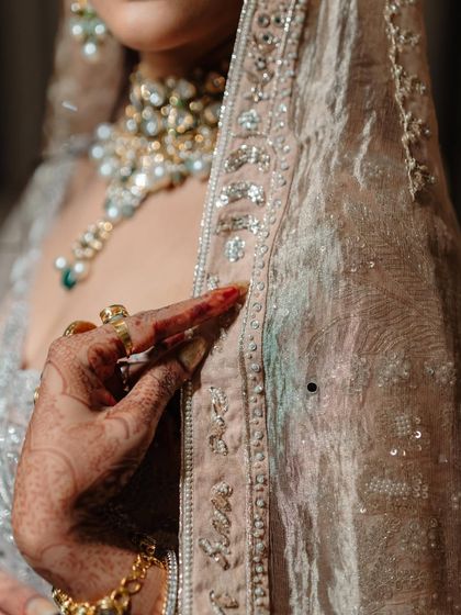Details matter. This close-up shows the harmony between the bride's henna, her jewelry, and the delicate texture of her outfit.
