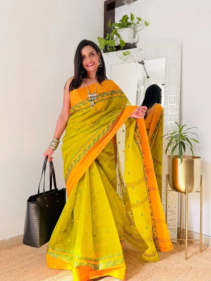 A bright and sunny yellow and orange Tant saree. This is a cheerful and vibrant option, perfect for daytime wear.
