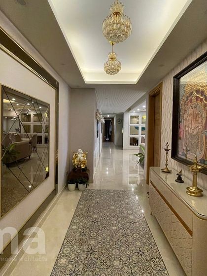 A full view of a long foyer hallway. The design uses a central patterned floor runner, a large geometric mirror, and a console with a traditional painting to create distinct zones and visual interest.