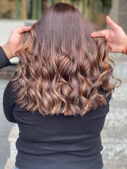The back view of this cool brown balayage showcases the beautiful blend of highlights and lowlights. The curls really make the different tones pop, creating a rich, textured look.