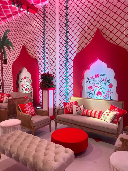 A cozy seating arrangement with a backdrop of red and white patterned walls featuring hand-painted floral motifs. The custom cushions continue the theme, ensuring every detail is perfectly coordinated.