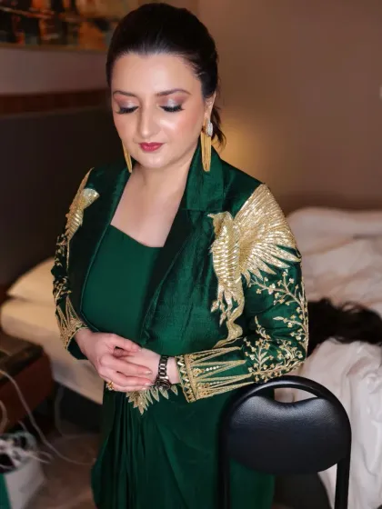 A sophisticated glam look for an evening party. The makeup features a shimmery bronze eye, a defined contour, and a classic red lip, paired with a sleek hairstyle to complement the ornate jacket.