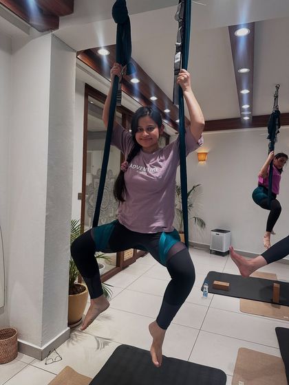 Another happy student enjoying the challenge and fun of aerial yoga. Her focused expression shows the mental engagement required for this dynamic practice.