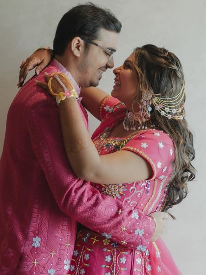 A sweet, close-up portrait of the couple in their vibrant pink outfits, their noses touching in a gesture of affection.