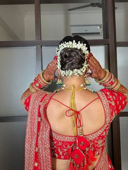The bride adjusts her gajra, giving a glimpse of the beautiful details of her hairstyle and her henna-adorned hands.