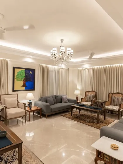 We designed this living room with a tranquil palette of cream and wood. The space is furnished with elegant pieces from Rosabagh, complemented by a large, vibrant painting that adds a pop of color. The overall effect is one of sophisticated calm.