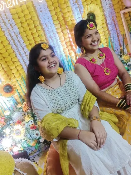 Happy faces at the Haldi ceremony. The bright yellow backdrop makes the colors of the outfits pop.