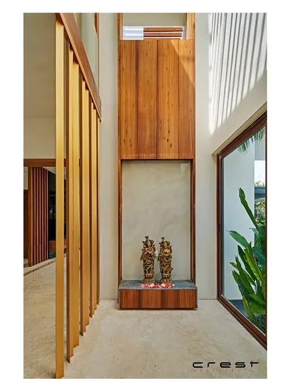 The double-height puja space in the 'Framed House.' Vertical timber slats and a high window create a serene, light-filled niche for spiritual reflection, showcasing our ability to craft modern sacred spaces.