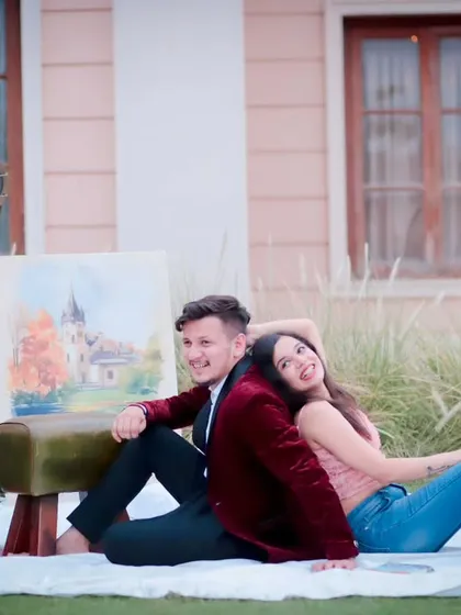 A fun and creative pre-wedding setup. This shot has a vintage, artistic feel, with the couple relaxing on a blanket outdoors, surrounded by props like a gramophone and an easel.