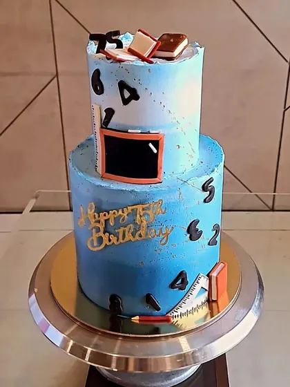 I made this two-tier cake for a teacher's 75th birthday. It's a custom theme with fondant details like a chalkboard, books, and rulers, all on a beautiful blue ombre base. The flavour inside was my rich Swiss Chocolate.