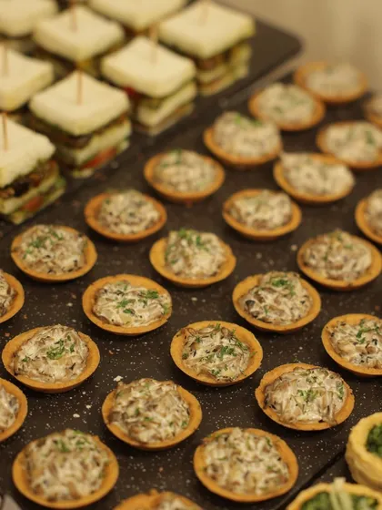 A closer look at the savory bites offered at a recent brand event. These mini mushroom tarts and layered finger sandwiches are crafted to be easily enjoyed while standing, making them a perfect choice for corporate mixers and launch parties.