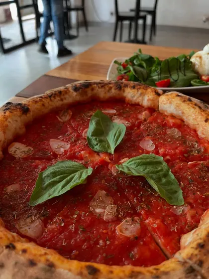 Our Marinara pizza in the background, with the focus on the fresh ingredients that make it special.