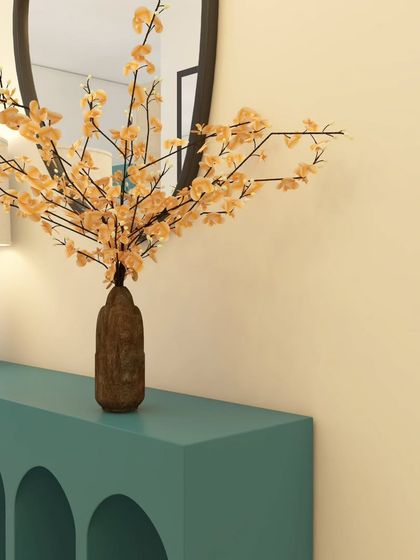 A detail shot of the arched console table. The clean lines and bold color make it a contemporary piece, while the textured lamp and rustic vase add a layer of warmth.