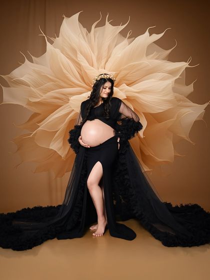 For this solo maternity portrait, we used a giant paper flower as a backdrop to complement the black ruffled gown. This creates a high-fashion, artistic look that is both bold and beautiful.