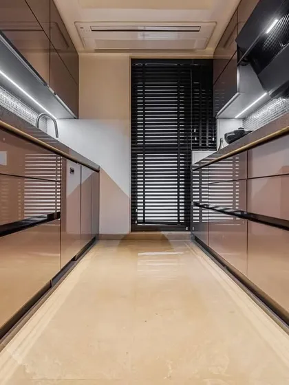 A sophisticated parallel kitchen with brown acrylic cabinets and under-cabinet lighting. The layout is perfect for a seamless cooking process, with everything organized and within easy reach.