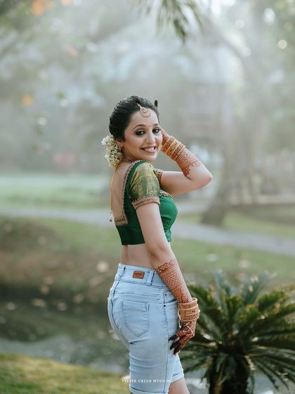 A fun and unique "getting ready" shot of the bride, Neha. This modern twist, pairing a traditional blouse with jeans, perfectly captures her personality.