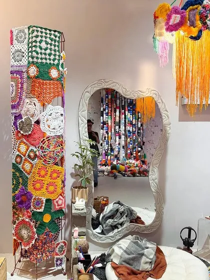 The 'Goblin Mode' space, designed as a sanctuary of informal comfort. A totem of vibrant crochet work stands beside a messy, lived-in setting, celebrating the joy of imperfection.