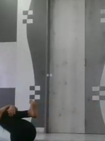 An instructor demonstrating Apanasana (Knees to Chest Pose) during an online evening class. This gentle pose is excellent for releasing lower back tension and calming the nervous system, perfect for winding down at the end of the day.