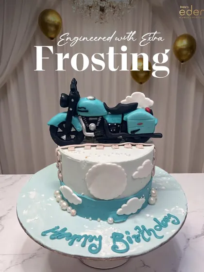 Engineered with extra frosting. This custom cake features a detailed, handcrafted motorcycle model on top of a sky-blue cake with clouds, perfect for the bike enthusiast's birthday.