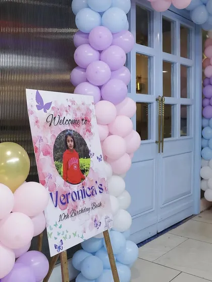 A personalized welcome sign at the entrance, featuring a photo of the birthday girl, invites guests to her glamorous 10th birthday bash.