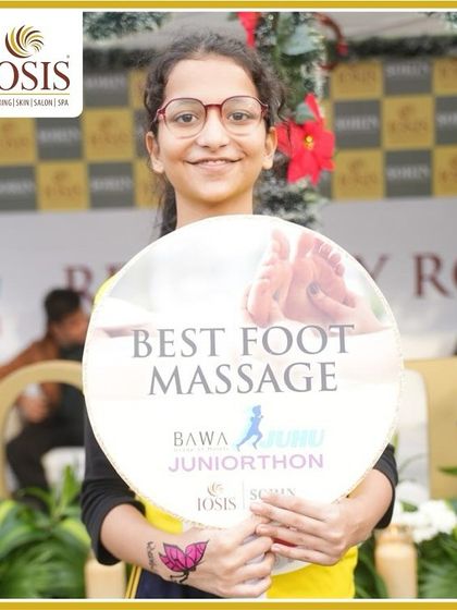 Every step deserves a little love. A young runner proudly shows off her butterfly face paint and a sign for our foot massage service at the Juniorthon event.