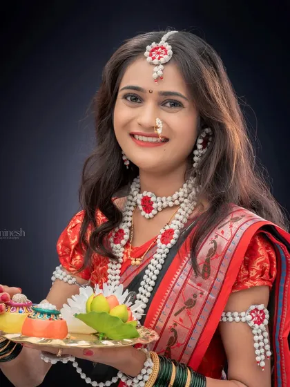 A woman dressed in a traditional saree and sugar jewelry holds a decorative platter. This is a classic portrait for the Makar Sankranti festival.