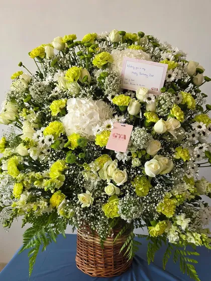 A slightly different angle of the white and green floral basket, showing the personalized card tucked within the blooms.