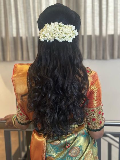 A simple half-updo with soft curls, decorated with a string of fresh jasmine flowers.