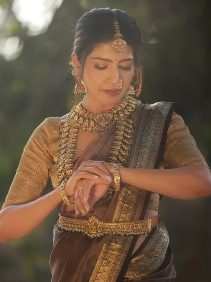A close-up of the model looking at her hands, a classic and elegant pose in traditional Indian photography. The soft outdoor light is perfect for this kind of shot.