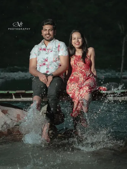 A playful moment captured during a pre-wedding shoot in Rishikesh, with the couple splashing their feet in the river at night.