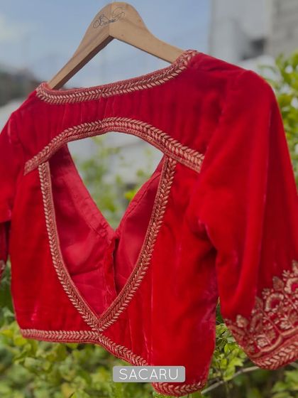 The stunning back design of the red velvet blouse, featuring a deep V-neckline and a keyhole cutout, both framed with elegant zardosi work.