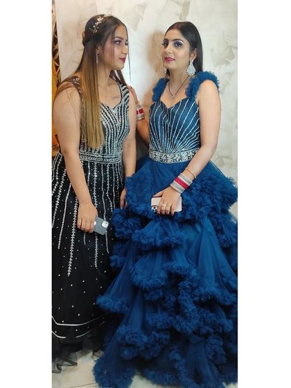 Two clients showing off their contrasting gown choices: one in a sleek black and silver sequin dress, the other in a voluminous royal blue ruffled gown.