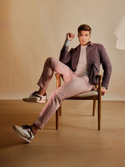 This seated view showcases the modern fit and bold color combination of the maroon shacket and pink trousers, perfect for making a fashion-forward statement.