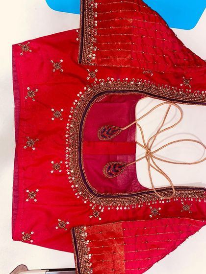 This red blouse is decorated with small sequin and bead motifs all over. The neckline and sleeves have a simple, elegant border.
