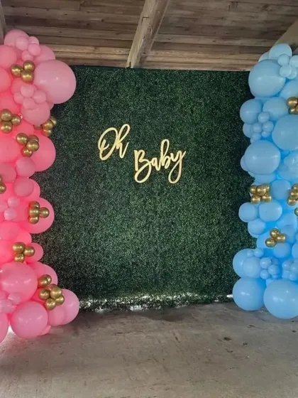 This is a classic gender reveal setup against a green hedge wall. I use two distinct balloon pillars, one pink and one blue, with a central 'Oh Baby' sign to build excitement.