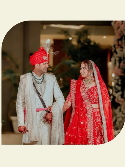 A beautiful portrait of Lokesh and Kritika, their loving gaze captured as they walk together, her red lehenga and his ivory sherwani perfectly coordinated.