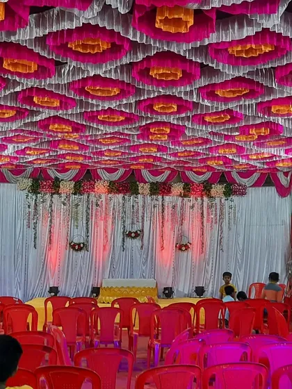 A wide view of the seating arrangement inside a beautifully decorated pandal for a Haldi event, with a vibrant pink, yellow, and white ceiling.