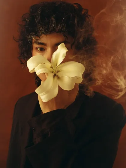 A creative shot using a slow shutter speed to capture smoke swirling around the model. This technique adds a dreamy, ethereal quality to the floral-themed portrait.