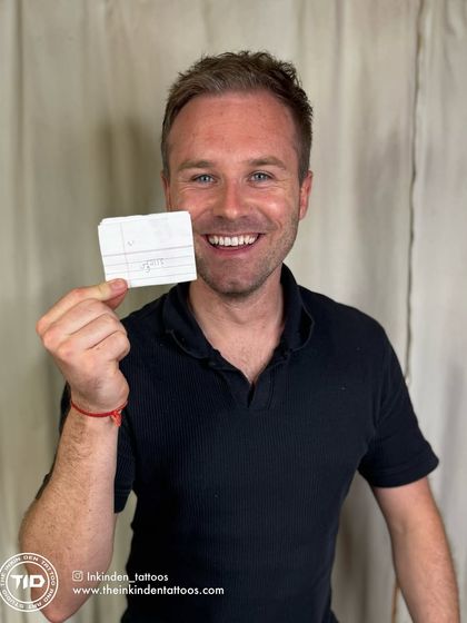 A happy client from Wales holding the original handwritten note for his "Jugaad" tattoo. This photo captures the joy of getting a meaningful piece of ink that connects him to his travels in India.