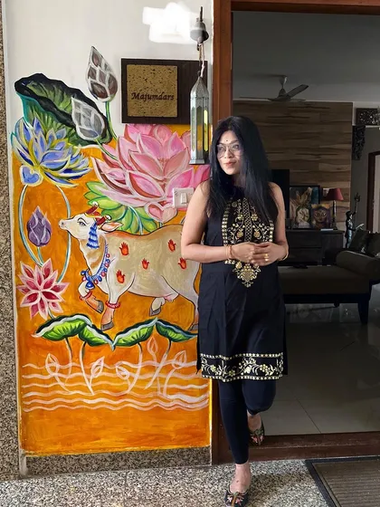 Here I am with a custom Pichwai-style mural I painted right at the entrance of my home. This piece, featuring a decorated cow and vibrant lotuses, shows how I adapt traditional Indian art to create a warm and personal welcome.