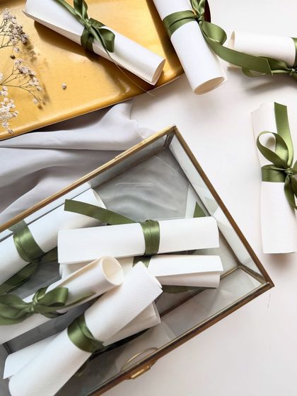 A collection of handwritten wedding vows, rolled into scrolls and tied with green silk ribbon. They can be presented in a beautiful glass box as a lasting memento of the wedding day.