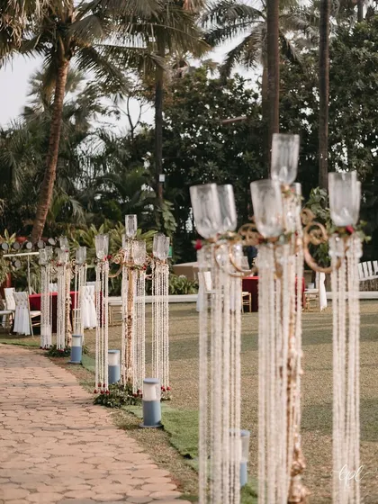 The aisle is lined with ornate candelabras draped in tuberose strings, guiding the way to the mandap.